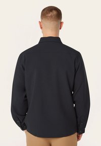 Zwart hemd met lange mouwen, een puntkraag, knoopmanchetten en een gladde textuur. Ontworpen met een rechte snit en een achterpand detail.