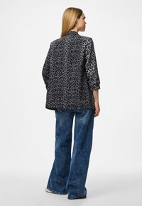 Leopardų rašto švarkas juodos ir pilkos spalvos, su laisvu siluetu, ilgomis rankovėmis ir lygiu paviršiumi, derinamas su plačiomis džinsinėmis kelnėmis.