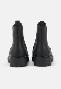 Melnas ādas potītes zābaki ar gludu apdari, elastīgām sānu daļām, vilkšanas cilpu un masīvām teksturētām zolēm.