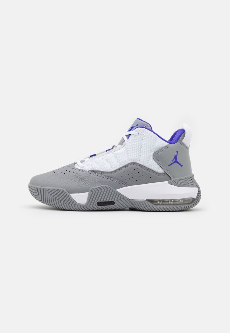 Chaussure de basket montante grise et blanche avec des accents violets, semelle texturée et amorti air visible au talon.