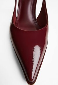 Pantof de tip slingback, lucios, de culoare roșu închis, cu vârful ascuțit și textură din piele netedă, pe un fundal alb.
