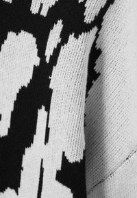 Tissu tricoté noir et blanc présentant un motif abstrait aux formes irrégulières, avec une texture douce et un poids moyen.