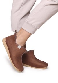 Bruna, texturerade tofflor med en mjuk foder, rund tå, flexibel sula och minimal sömnadsdetalj. Bärs med ljusa byxor.
