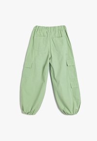 Groene cargobroek met elastische tailleband, geraffineerde manchetten en meerdere zakken, met een zachte katoenen textuur en een relaxte pasvorm.