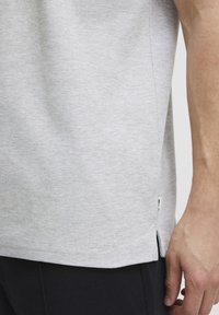 Lys grå T-shirt med korte ærmer lavet af blød bomuld, med en let struktureret overflade og sideslids i kanten for bedre bevægelsesfrihed.