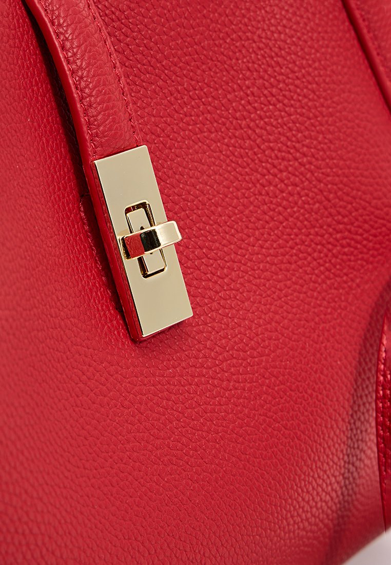 Sac à main en cuir rouge avec une finition texturée et un fermoir rectangulaire doré.