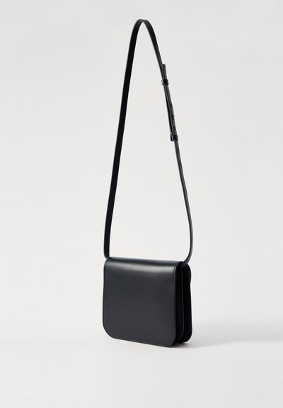 Black leather crossbody bag with a smooth texture, rectangular shape, adjustable strap, and a magnetic flap closure.