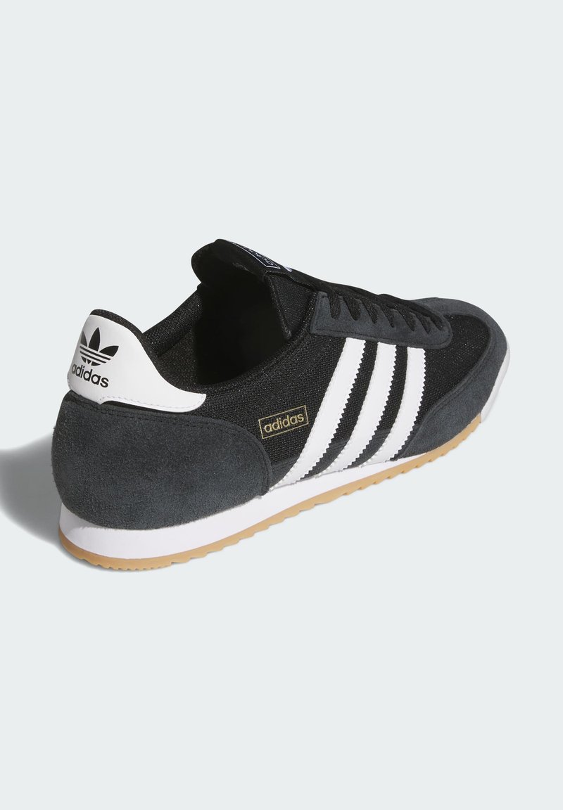Schwarz-weißer Adidas-Sneaker mit drei weißen Streifen, Veloursleder-Ferse, Gummisohle und Adidas-Logo auf der Fersenschlaufe und der Seite.
