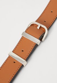 Brunt læderbælte med glat tekstur, sølvfarvet metalspænde og detaljer. Har flere justeringshuller til fastgørelse.