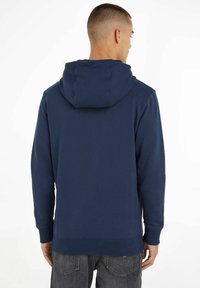 Felpa blu navy con cappuccio regolabile, polsini e orlo a coste, realizzata in un tessuto morbido; presenta una vestibilità comoda e un design semplice.
