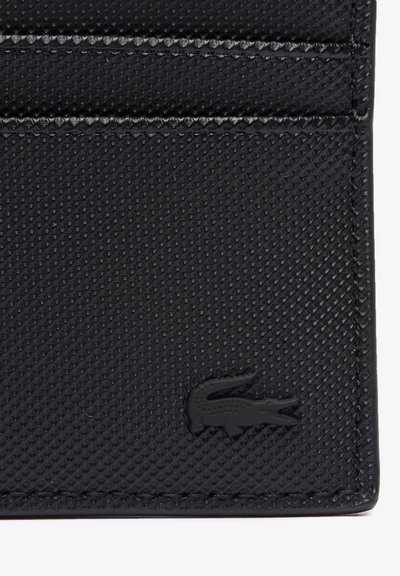 Porte-cartes noir avec une surface texturée, comportant trois fentes pour cartes et un subtil logo. Fabriqué en matériau synthétique.