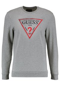 Sudadera gris hecha de una mezcla de algodón, con un logo triangular rojo y negro que dice "GUESS U.S.A." y "?". Mangas largas, cuello redondo.