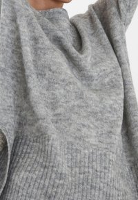 Světlé šedé pletené svetr vyrobený z měkkého materiálu, s uvolněným střihem, žebrovanou texturou na lemu a volným designem výstřihu.