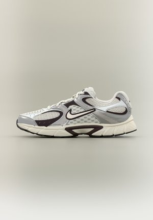 Weißer und grauer Nike-Laufschuh mit Mesh-Einsätzen, schwarzen Akzenten und gedämpfter Sohle, dargestellt vor einem einfarbigen Hintergrund.