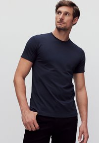 Marineblaue Kurzarm-T-Shirt aus weichem Baumwollstoff, mit Rundhalsausschnitt und tailliertem Design, präsentiert auf einem Modell.
