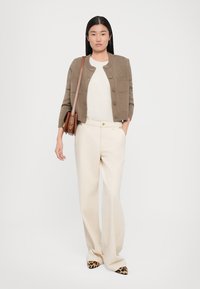 Brun strikket cardigan med knappelukking, hvit topp, beige vide bukser og dyreprint spisse sko. Inkluderer en brun skulderveske.
