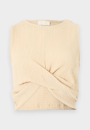 Ærmeløs top i tekstureret, lys beige stof. Har et snoet frontdesign og en rund halsudskæring. Glat finish med rynkede detaljer ved kanten.