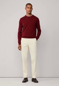 Vinröd tröja med rund hals, kombinerad med krämfärgade byxor och mörkbruna skor. Mjuk textur och smal passform. Enkel och modern stil.