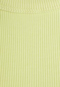 Ljust gult ribbat tyg med en mjuk struktur, som har horisontella linjer och en ren kant söm upptill.