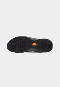 Semelle de chaussure noire et robuste avec un motif de crampons multidirectionnels profonds et un logo Vibram orange au centre.