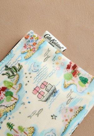 Stofpose med et farverigt, illustreret kystlandskab med huse, både og blomster. Lyseblå baggrund med detaljerede mønstre.
