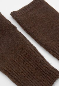 Mânuși fără degete din lână maro, cu o textură ribbată, realizate dintr-un material moale și gros. Designul este simplu și călduros, ideal pentru vreme rece.