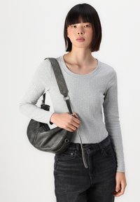 Gray ribbed long-sleeve top, black jeans, and a slouchy gray handbag with a silver strap; the bag features a smooth texture and curved shape.