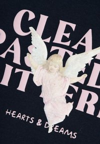 Tessuto nero con grande testo rosa, "CLEA PASTEL PATTERNS," accompagnato da una grafica di un angelo luccicante in colori pastello e le parole "HEARTS & DREAMS" sottostanti.