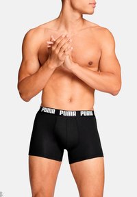 Schwarze Boxershorts aus weichem Stoff, mit einem breiten elastischen Bund, auf dem das "PUMA"-Logo in weißen Buchstaben aufgedruckt ist.