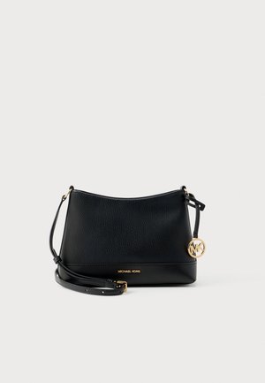 Borsa a tracolla in pelle nera Michael Kors con tracolla regolabile e ciondolo con logo MK dorato su sfondo chiaro semplice.