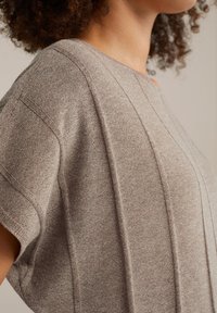 Brun stickad topp med korta ärmar, med texturerade ränder och en avslappnad passform. Mjuk material med en slät yta.