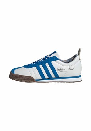 Biało-niebieski but sportowy Adidas Samba z gumową podeszwą, trzema niebieskimi paskami i kratkowaną podszewką, widoczny z boku.