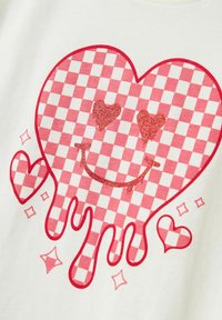 Tela blanca con un gráfico de corazón a cuadros en rojo y rosa, con acentos de purpurina, gotas que parecen derretirse, y pequeños corazones y estrellas.