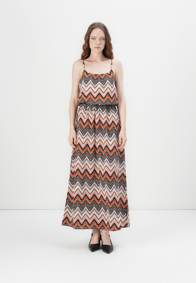 Maxi-jurk met een zigzagpatroon in oranje, zwart en wit. Gemaakt van lichtgewicht stof met dunne schouderbandjes en een elastische taille.