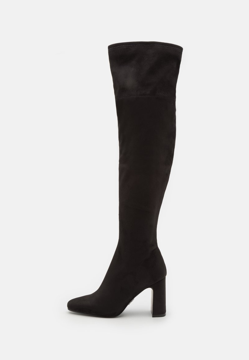 Bottes noires au-dessus du genou en tissu souple, avec un bout pointu et un talon épais, présentant une texture lisse et sans embellissements visibles.