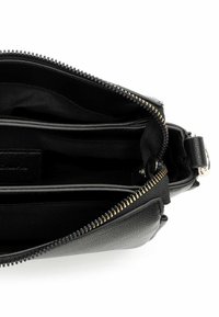 Czarna skórzana torba z złotym zamkiem błyskawicznym, posiadająca wiele wewnętrznych przegródek oraz teksturowaną powierzchnię. Dodatki obejmują metalowe elementy dekoracyjne.
