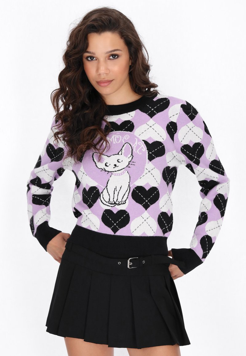 Sweter z dzianiny z wzorem serc w kolorach czarnym, białym i lawendowym, z białym wzorem kota na środku, zestawiony z czarną plisowaną spódnicą.