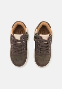 Bruna canvas sneakers med en krämfärgad läderdetalj, rund tå, snörningsdesign, perforerad detaljering och sidogömda dragkedja för enkel på- och avtagning.