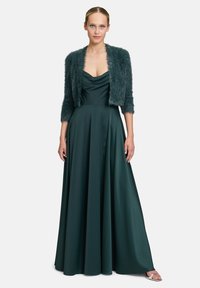 Tealfarbenes Satin-Abendkleid mit einem drapierten Ausschnitt und einem fließenden Rock, kombiniert mit einer strukturierten, kurzen, pelzigen Jacke.