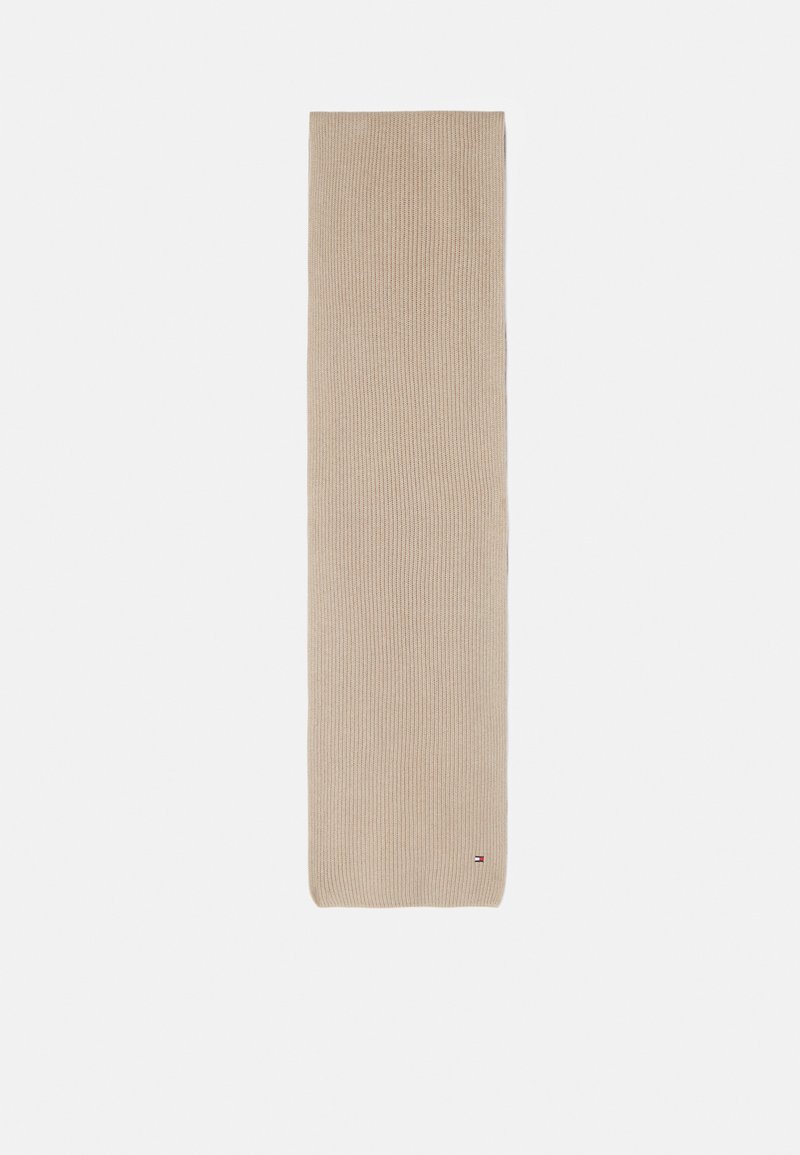 Beige strikket tørklæde med riflet tekstur, forlænget form og små logo-detaljer i bunden. Egnet til forskellige stilarter og årstider.
