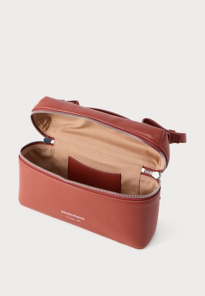 Καφέ δερμάτινη τσάντα ώμου με φερμουάρ, με μπεζ υφασμάτινη επένδυση και μια μικρή εσωτερική τσέπη, με λογότυπο Emporio Armani μπροστά.