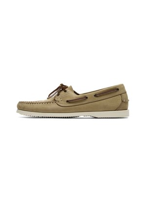 Chaussure bateau en cuir beige avec détail lacet marron, semelle blanche en caoutchouc et coutures mocassin le long de l’orteil et des côtés.