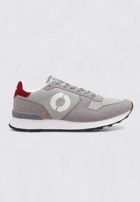 Baskets grises et blanches avec un onglet de talon rouge, un logo circulaire sur le côté, des lacets gris et une semelle noire, présentées de l'extérieur sur un fond blanc.