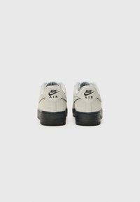 Gray suede sneakers with a black rubber sole, featuring "Nike Air" branding on the heel and a textured gray mesh tongue.