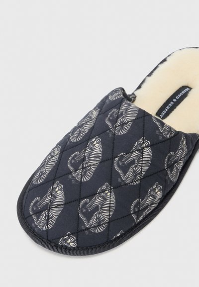 Lapanan quilted navy dengan pola harimau berwarna putih dan abu-abu, dilengkapi dengan lapisan lembut berbulu dan trim hitam yang diperkuat pada sol.