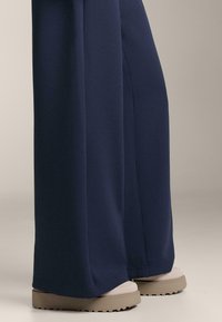 Námornícke široké nohavice vyrobené z hladkej tkaniny, skombinované s béžovými platformovými sandálmi s textúrovanou podrážkou.