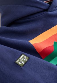 Navy fleece hoodie with a large multi-colored graphic design featuring orange, red, and green stripes. Includes a green patch label.
