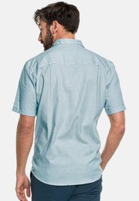 Camisa de botones de manga corta en azul claro con un patrón de cuadro sutil, corte relajado y un cuello estructurado. La parte trasera presenta un yugo en los hombros.