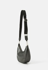 Borsa a spalla sintetica nera con design curvo, texture lucida, cerniera argento e tracolla regolabile con logo "GUESS".