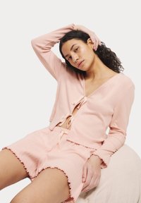 Roze geribbelde tweedelige set met een cropped top met een striksluiting en bijpassende shorts met een ruche rand, ontworpen voor comfort.